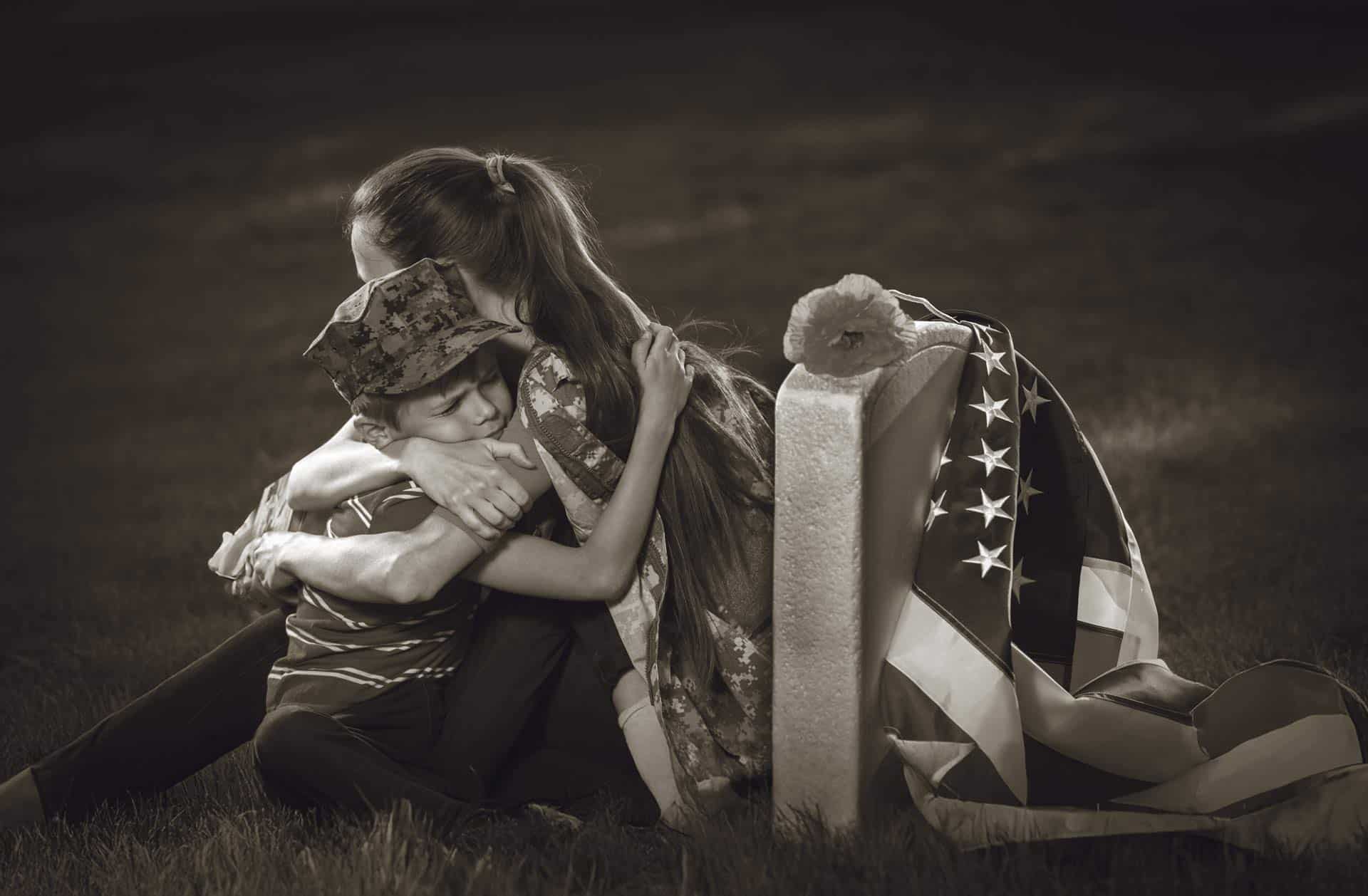 Mother and son comfort each other near tombstone